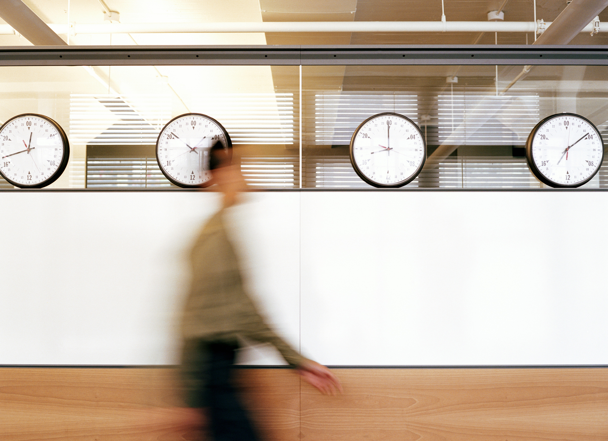 Businessman walking by wall clocks showing different time zones