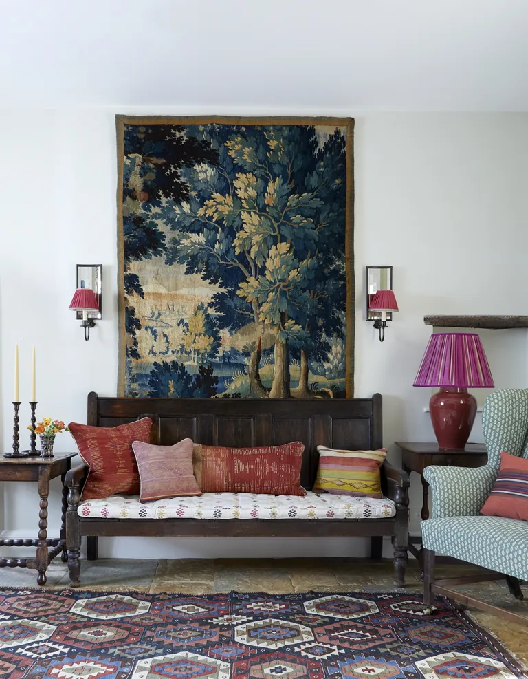 living room with stone floor, wall hanging, wall lights, vintage bench, armchair, sigh, table lamps, side tables