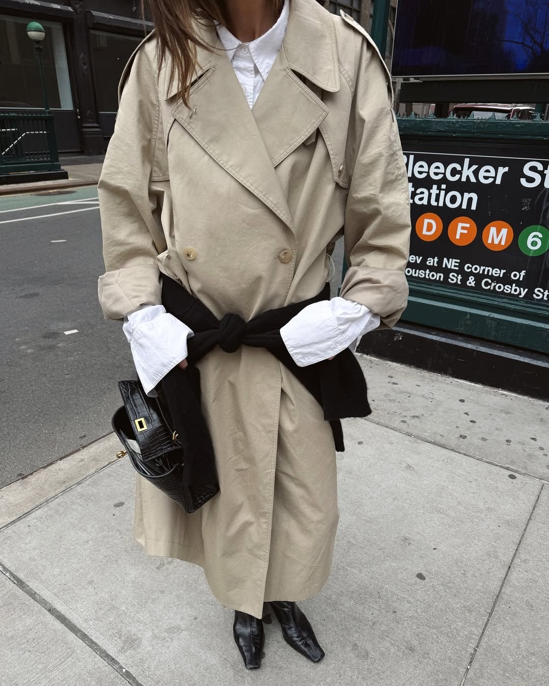 @cocoschiffer in a trench coat, white button-down, black boots, and a black leather handbag