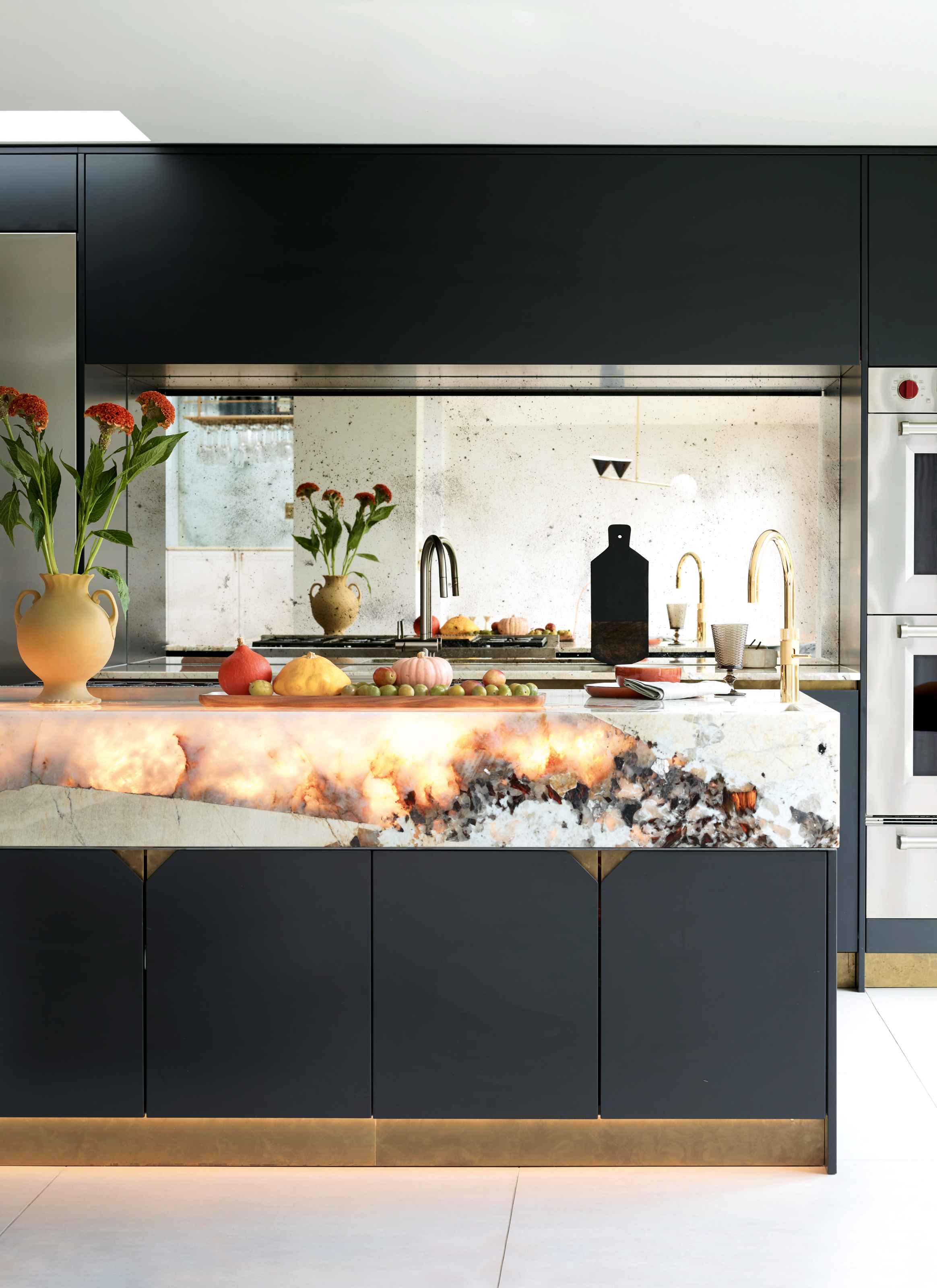Sleek black kitchen with deep white marble worktop with backlit stone elements