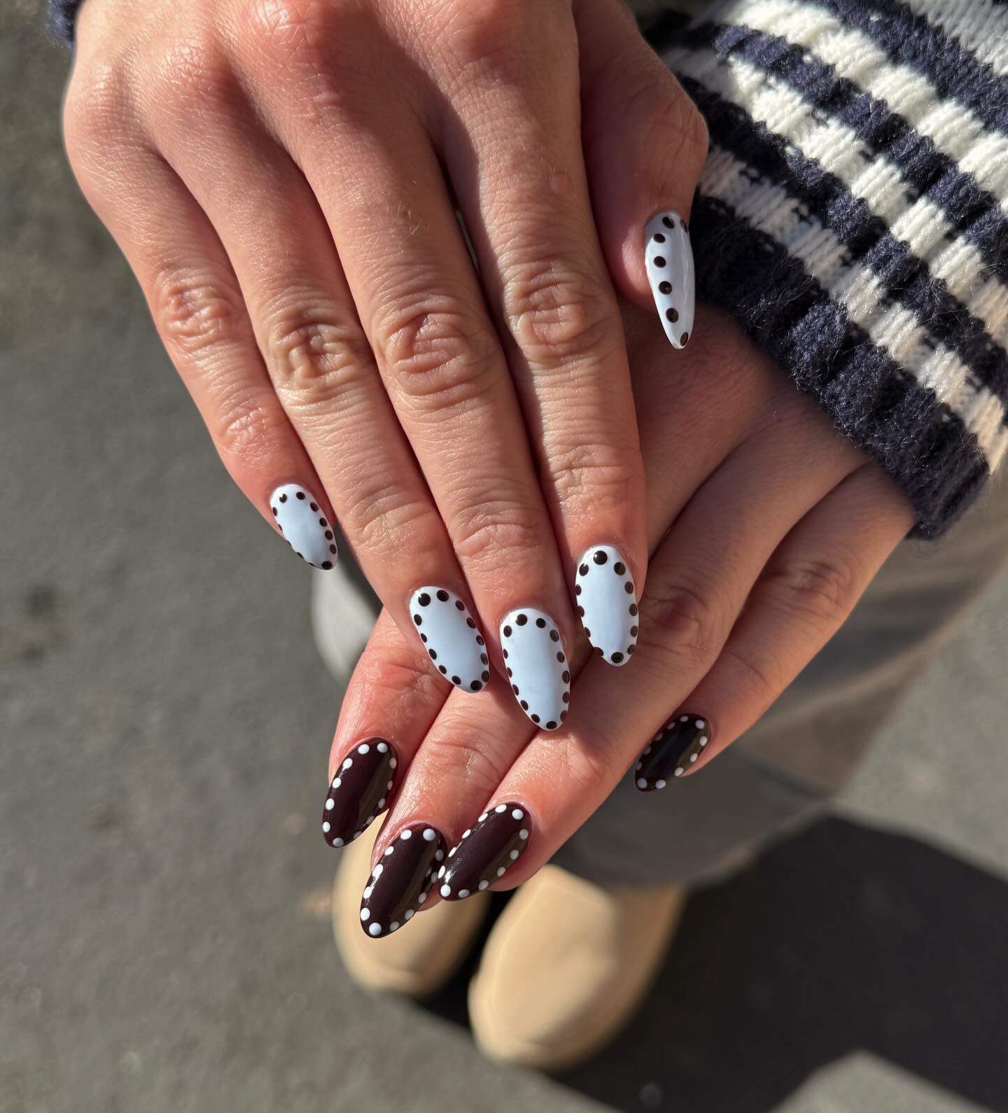 Mismatched pale blue and brown nails with contrast polka dots.