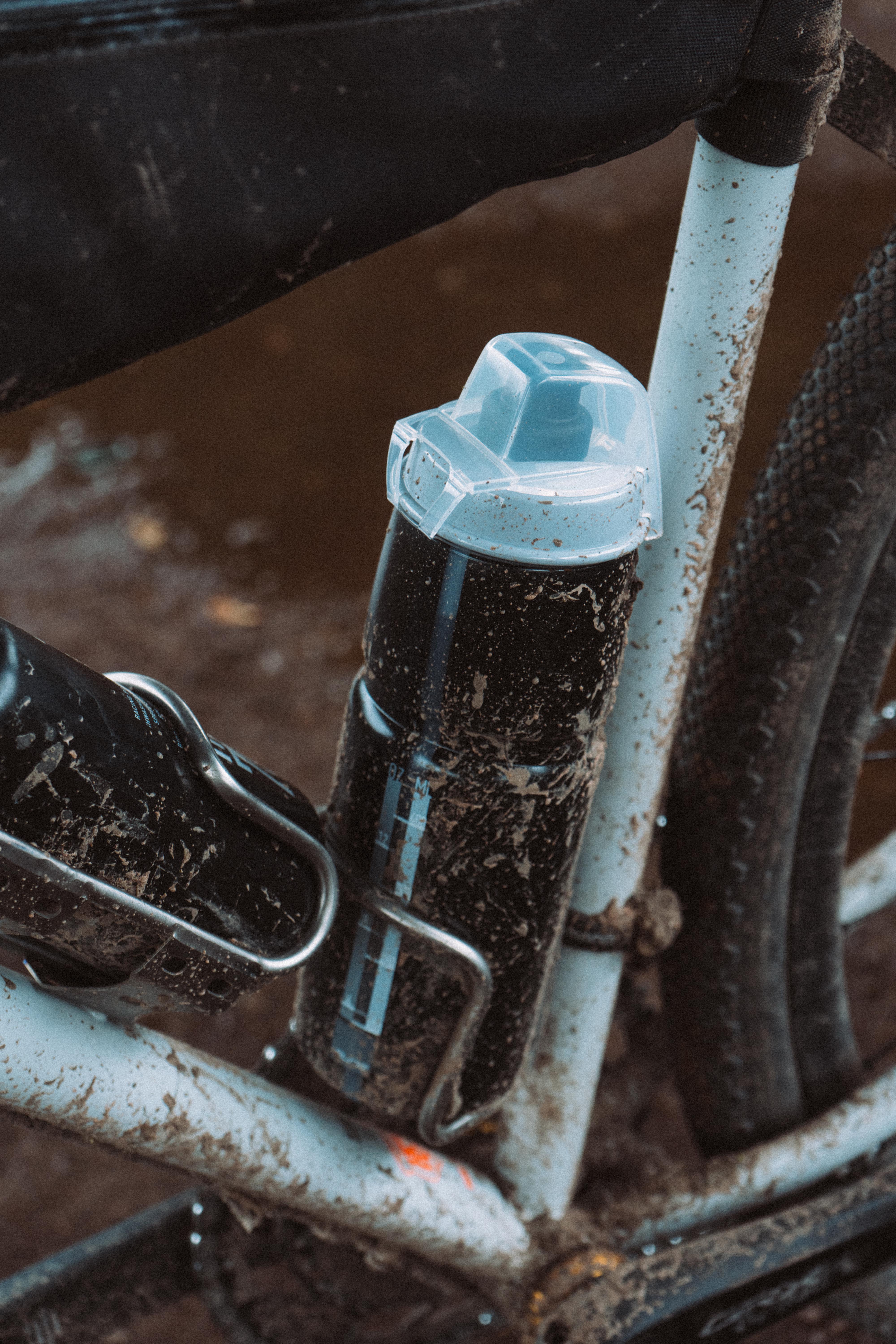 A black water bottle with a clear cap mounted to a black bike frame