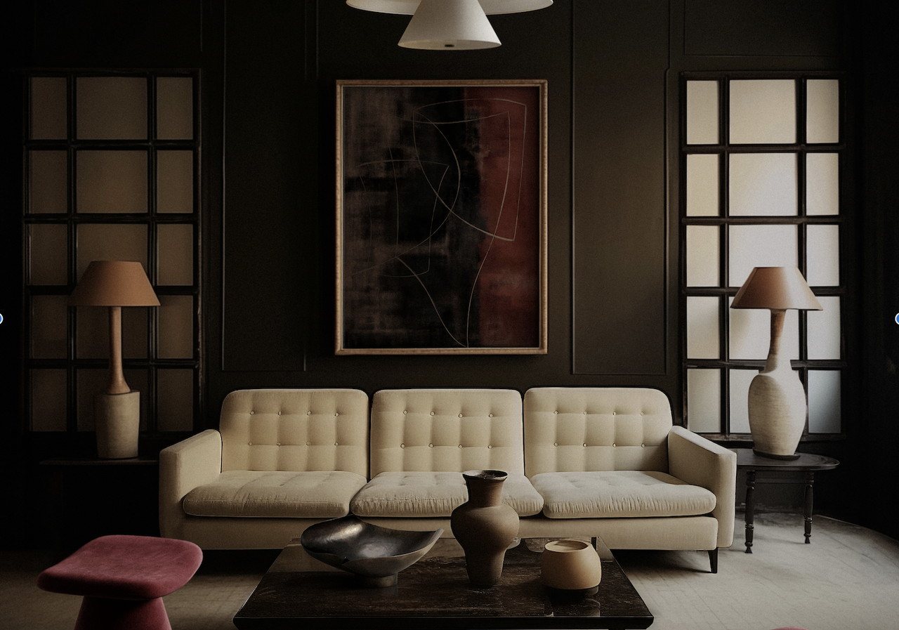 A living room with a cream sofa, and dark brown walls, along with plum stools