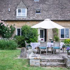 exterior of stone cottage with outdoor dining on terrace