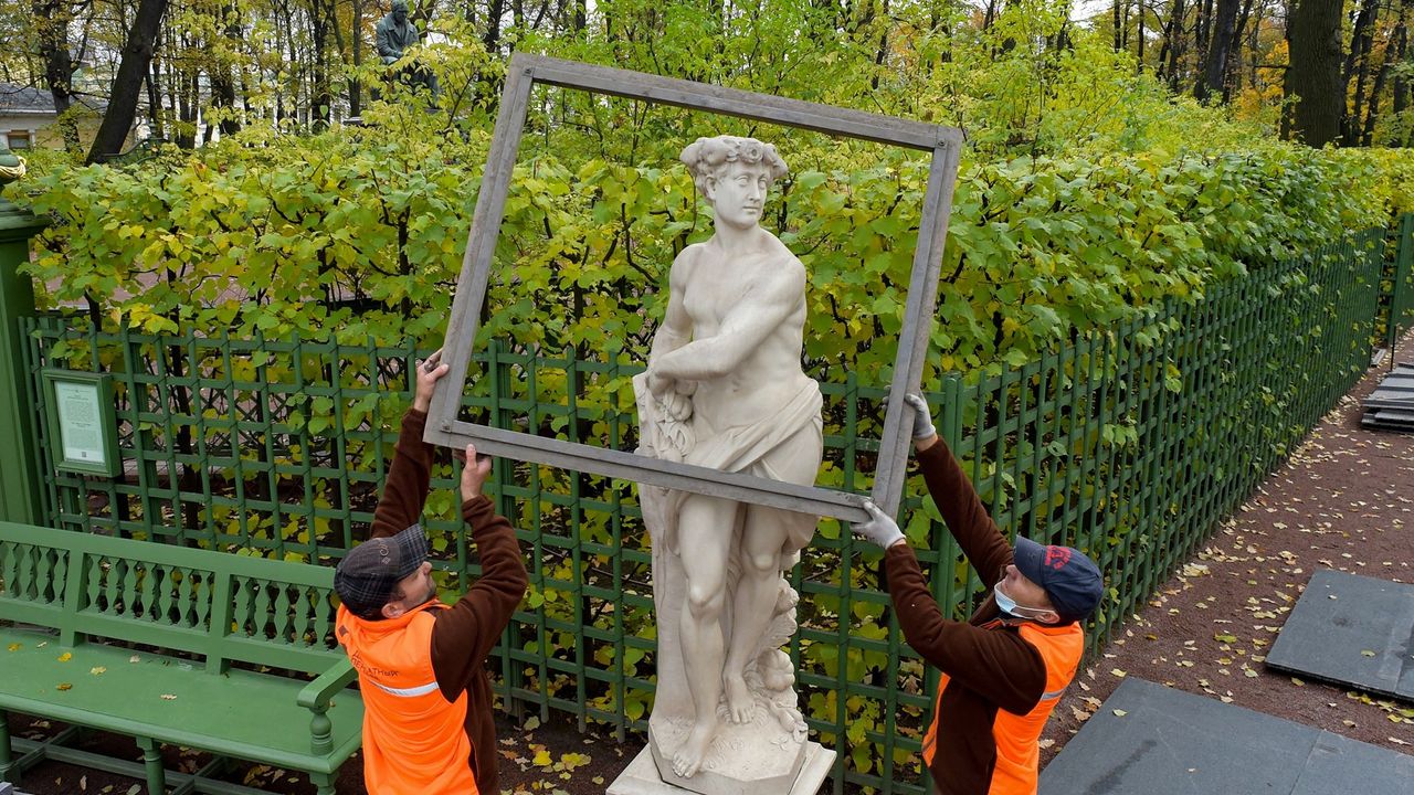 Workers cover a sculpture with a wooden case to protect it during winter at the Summer Garden in Saint Petersburg