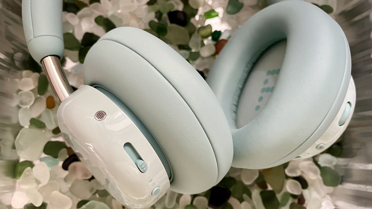 CMF Headphone Pro in pistachio green held in a hand or hung on a barbell, being pushed up by a carved frog