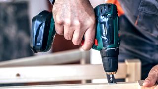 Cordless drill screwing screw into wood