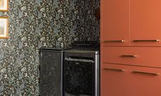 a laundry room with orange cabinetry and wallpaper