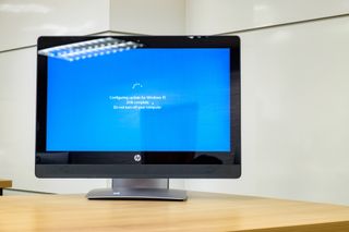 PC monitor on a desk stuck on the Windows 10 update screen