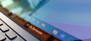 A black ASUS Zenbook Pro 14 OLED sitting on a patio in front of a grassy lawn