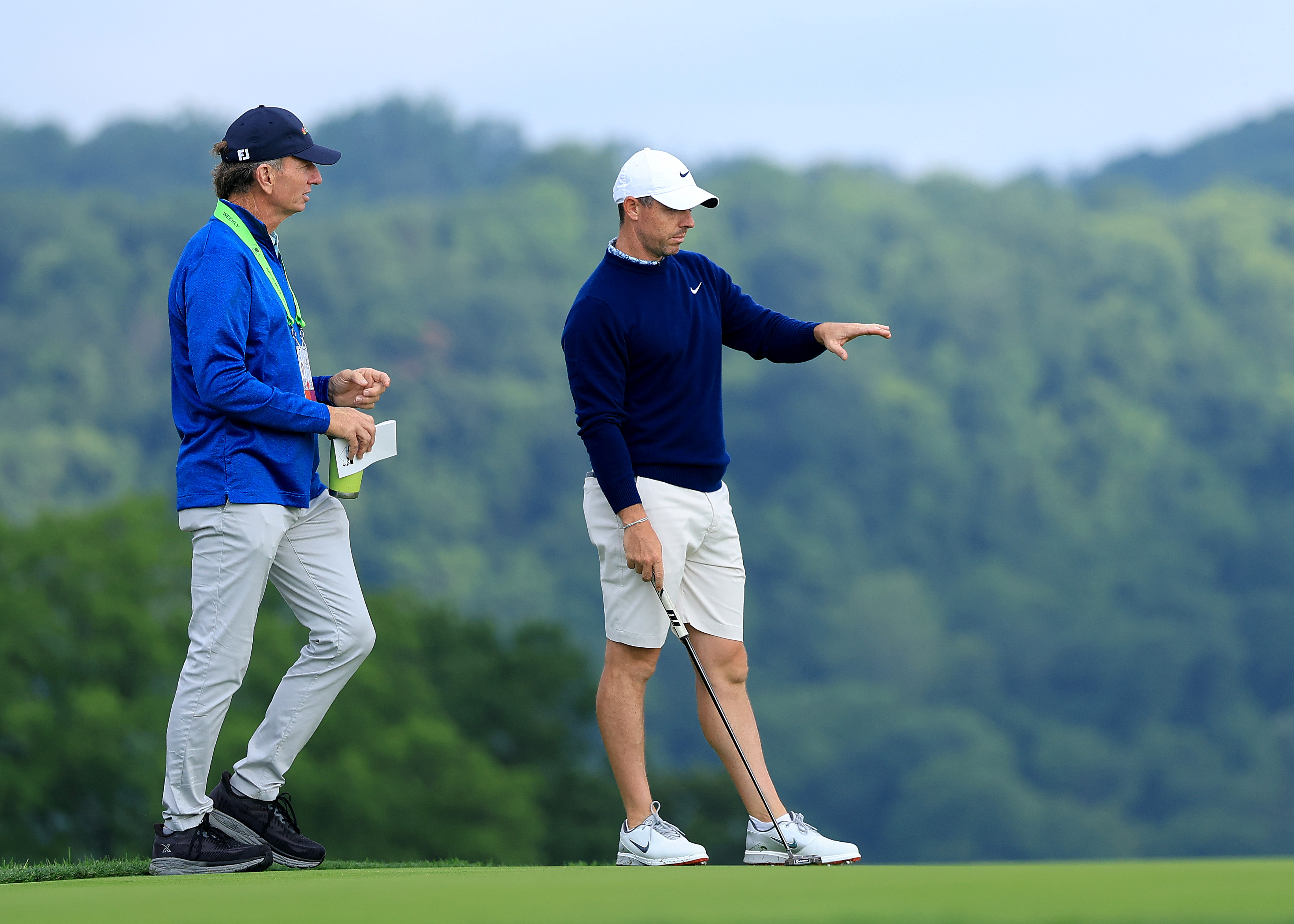 Brad Faxon and Rory McIlroy chat on the green during a practice round at the US Open