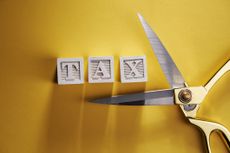 image of scissors open to cut the word taxes on wooden blocks