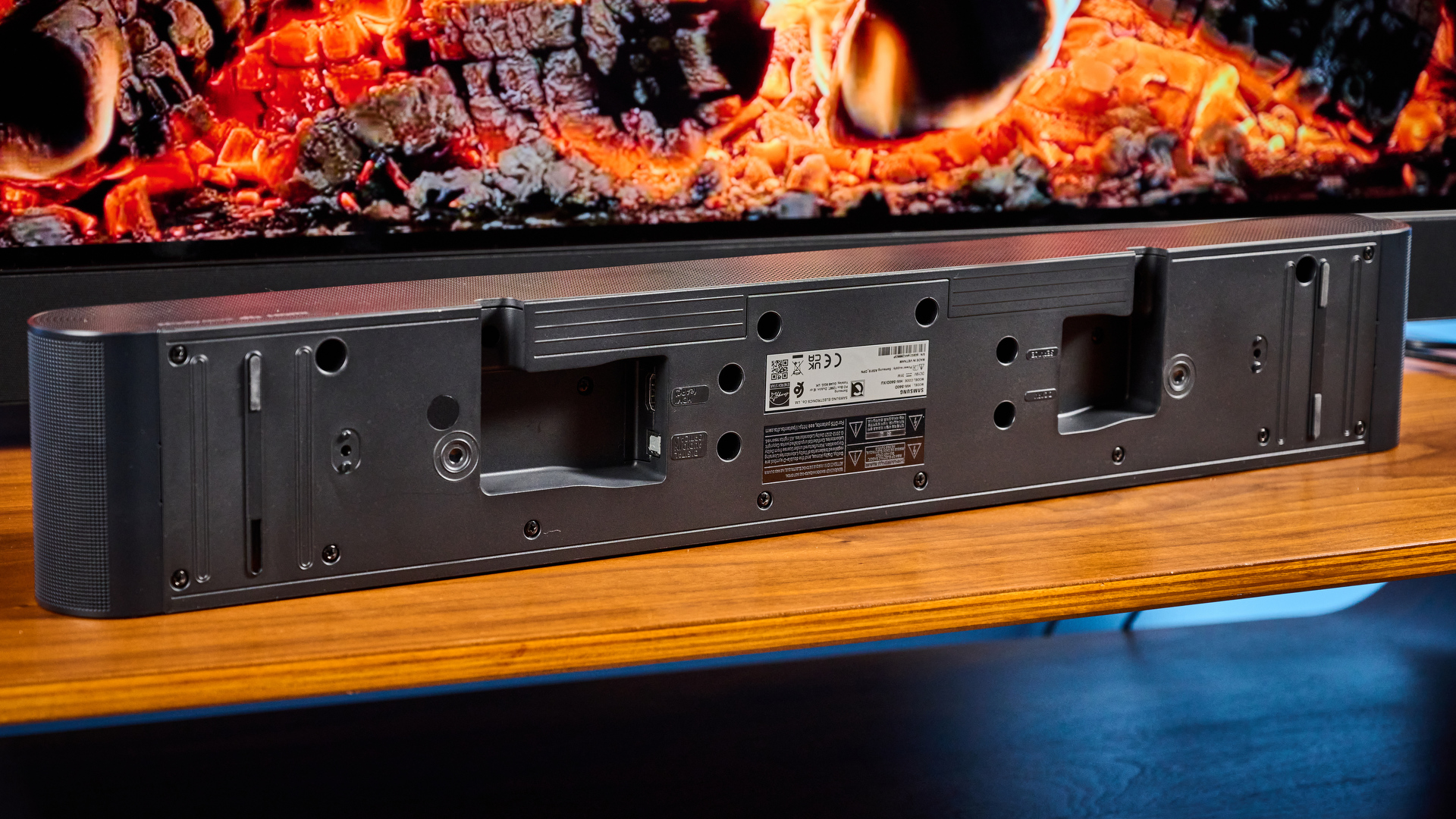 the samsung hw-s60D soundbar photographed on a wooden coffee table with a panasonic tv and a samsung soundbar against a blue background