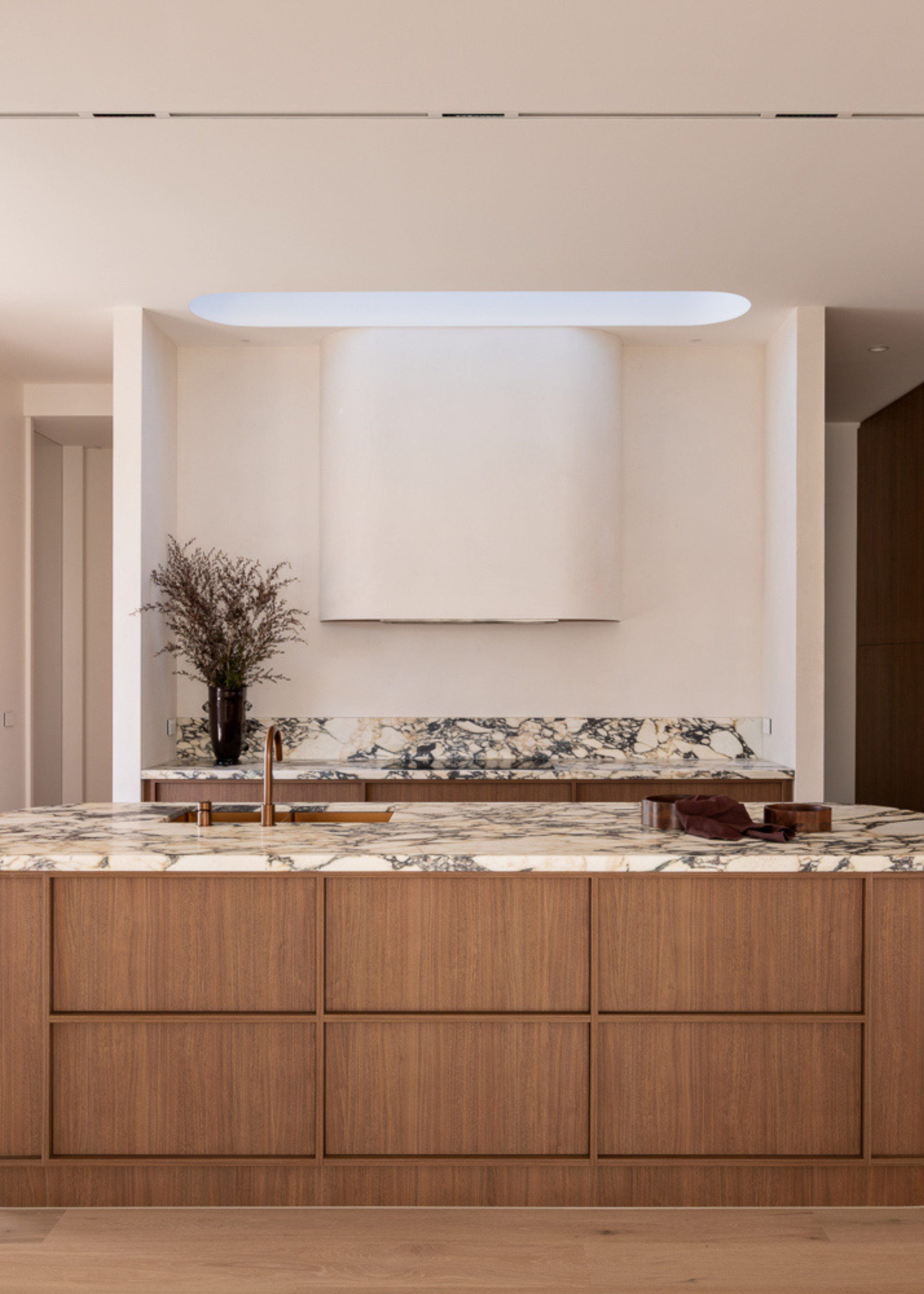 A white kitchen with a wood island, and a marble countertop and backsplash