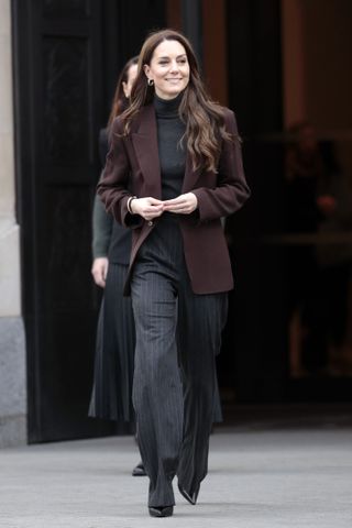 Kate Middleton wears pinstripe trousers.