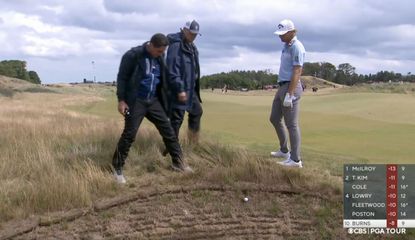 Burns chats to a rules official with golf ball hanging over a bunker