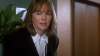 Diane Keaton in a black jacket and white shirt, looking annoyed.