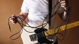 Man holding a guitar cable in his hands