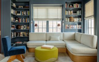 home library snug with blue walls and shelvesm light colored sofa