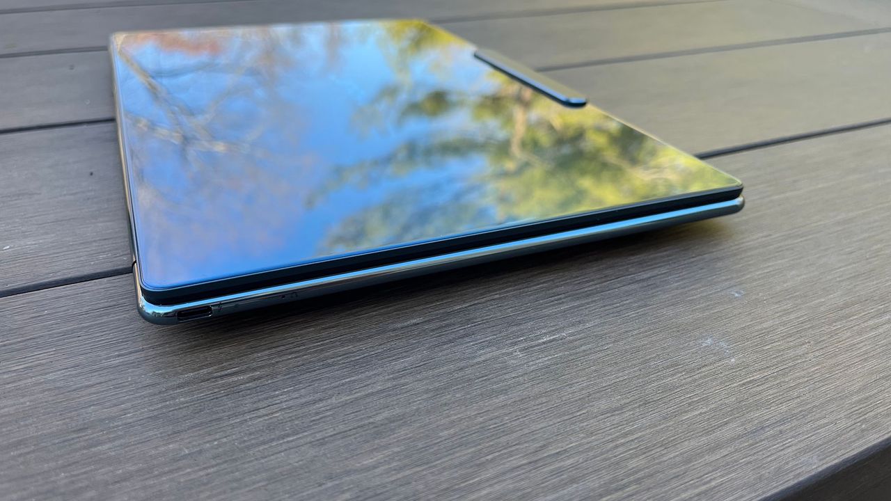 A Lenovo Yoga Slim 9i sitting on a picnic table outside at an angle