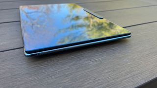 A Lenovo Yoga Slim 9i sitting on a picnic table outside at an angle