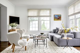 white living room with light grey sofa and two white accent chairs in white boucle