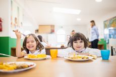 Children sat at a table eating a school dinner