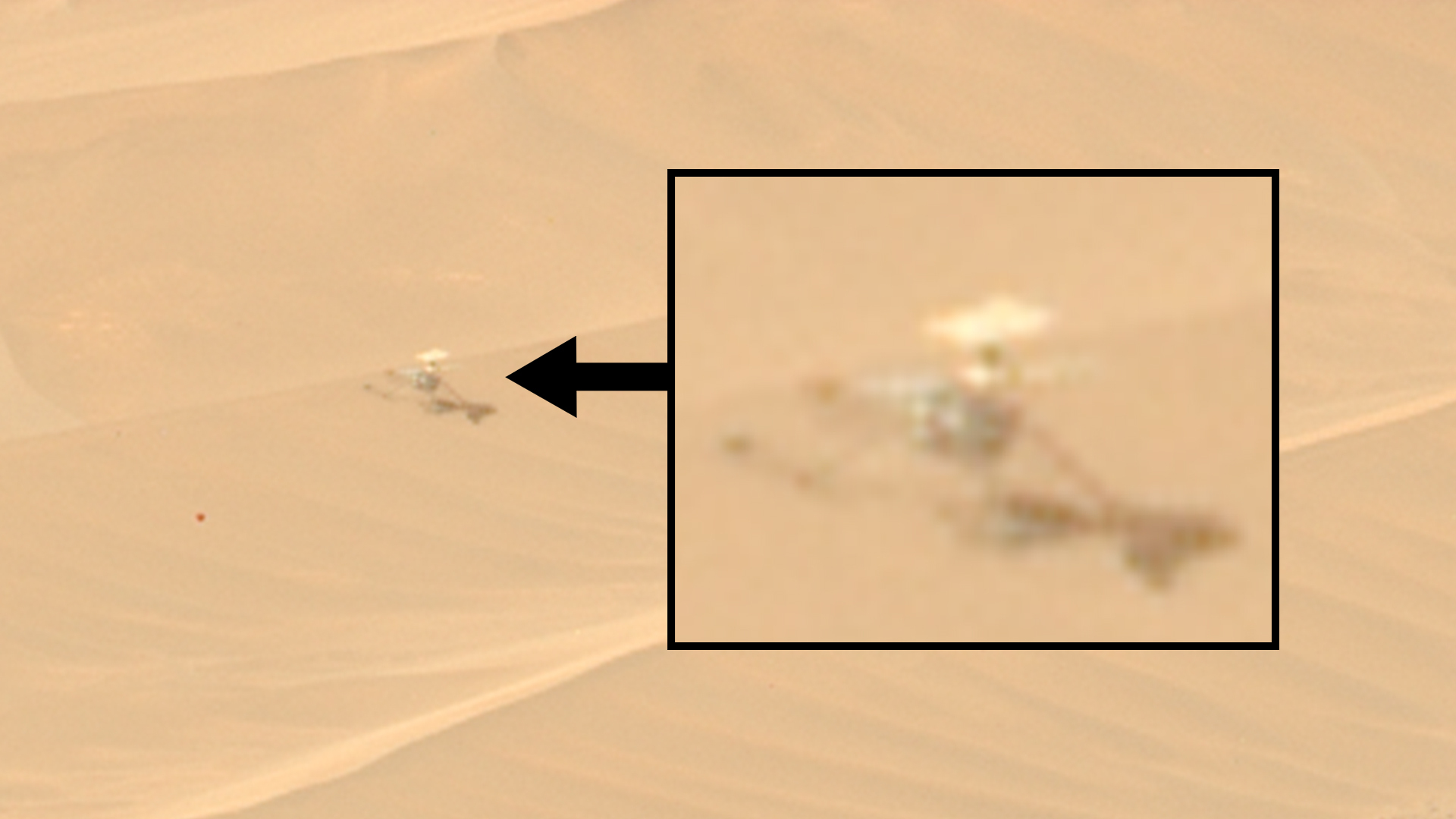 a small helicopter-like drone can be seen motionless on a reddish-orange sand dune
