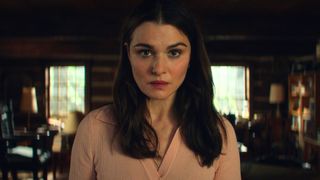 Rachel Weisz stands in the middle of a log cabin