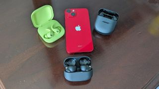 Bose, Best and Sony earbuds with red iPhone on a desktop