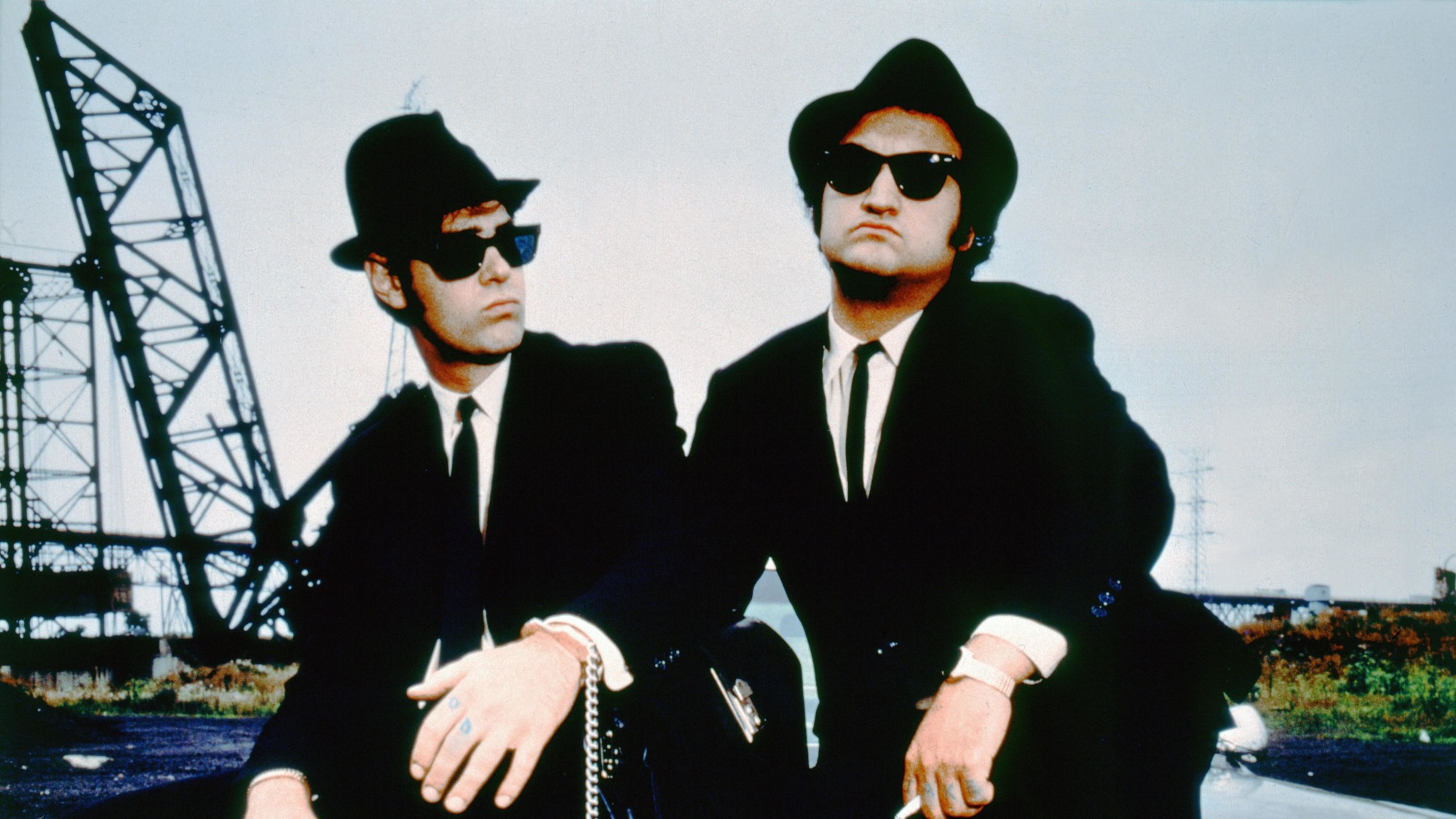 Dan Aykroyd and John Belushi in black suits with sunglasses and fedoras in The Blues Brothers