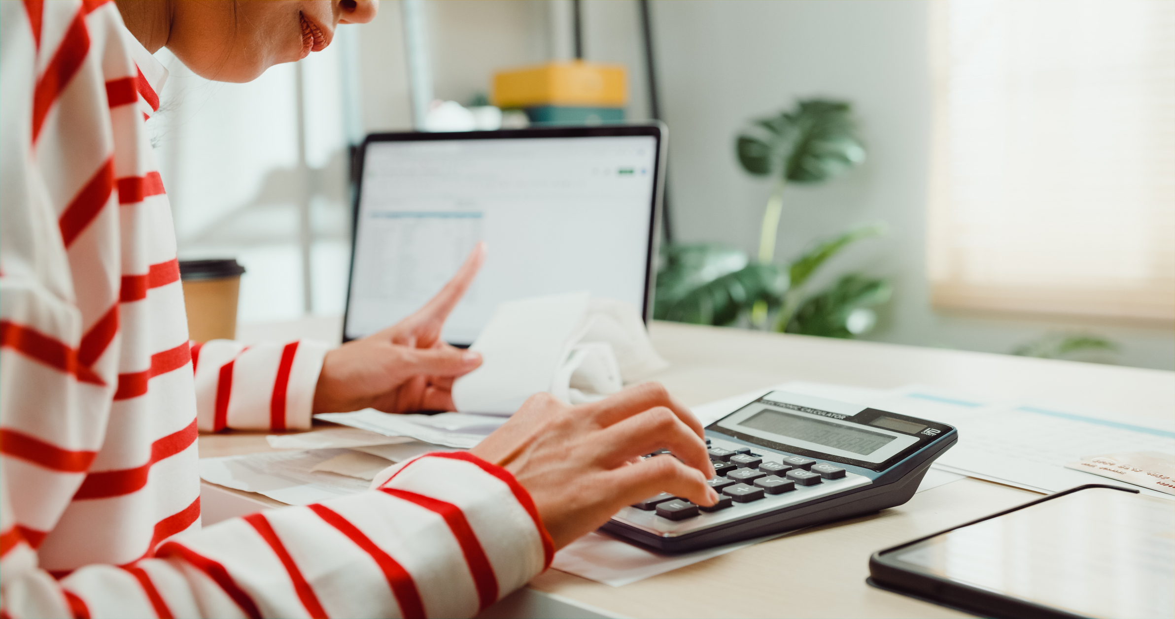 A woman using a calculator sitting at a desk