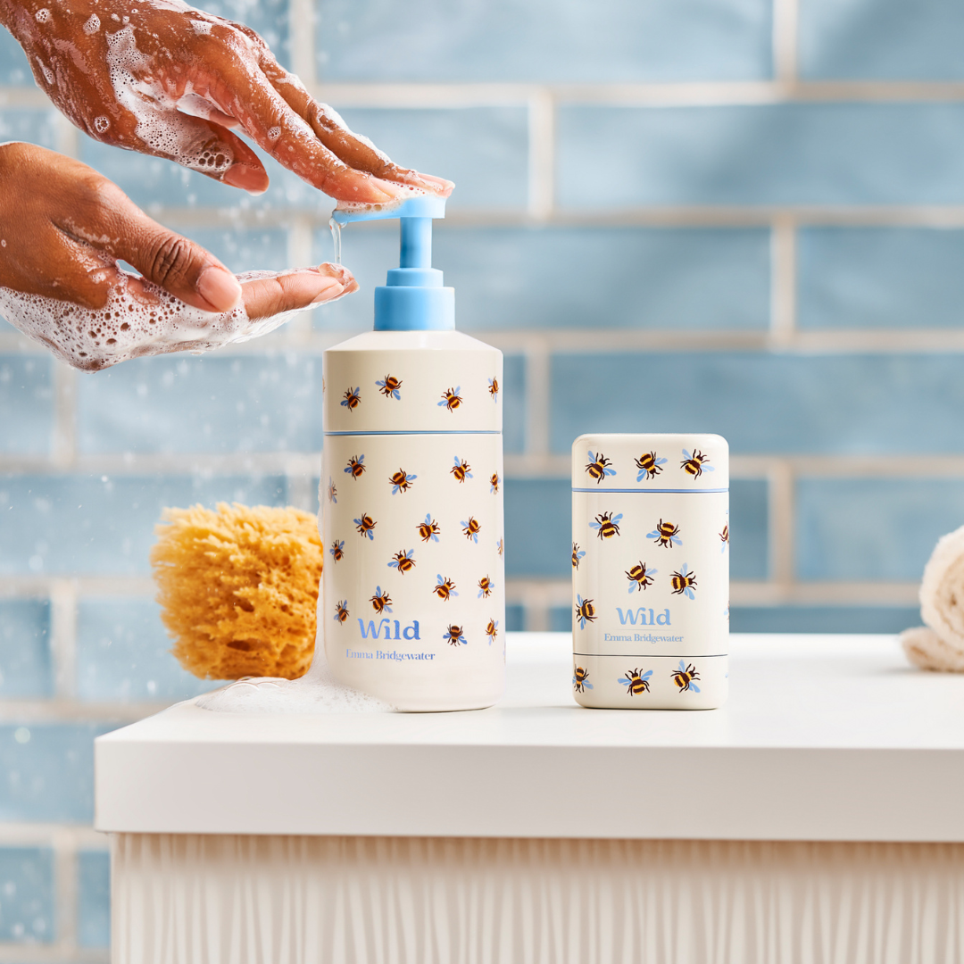 Woman using Wild Emma Bridgewater Bee handwash and deodorant in her bathroom, blue tiles on background.