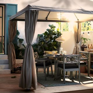 curtained gazebo with hanging lamp and dining table with armchairs