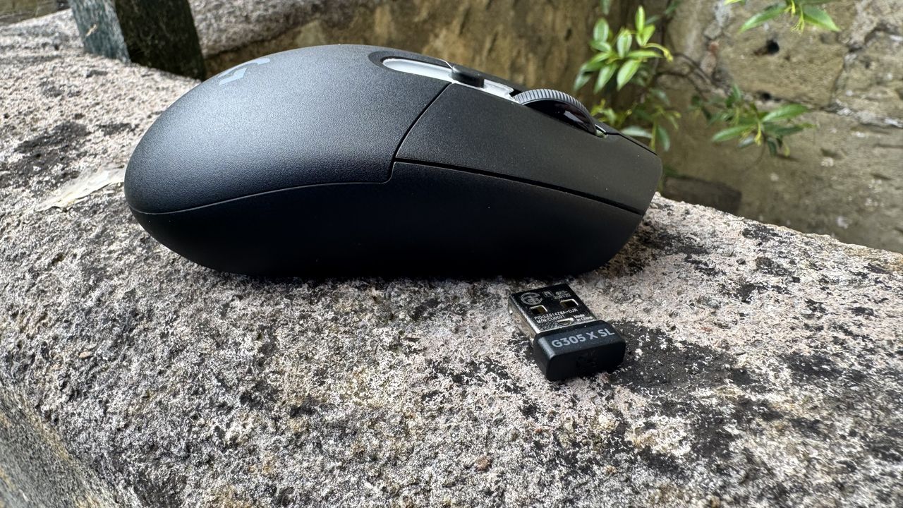 Logitech G305 X Superlight gaming mouse with its receiver, on top of stone