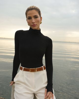 woman in black turtleneck and white pants