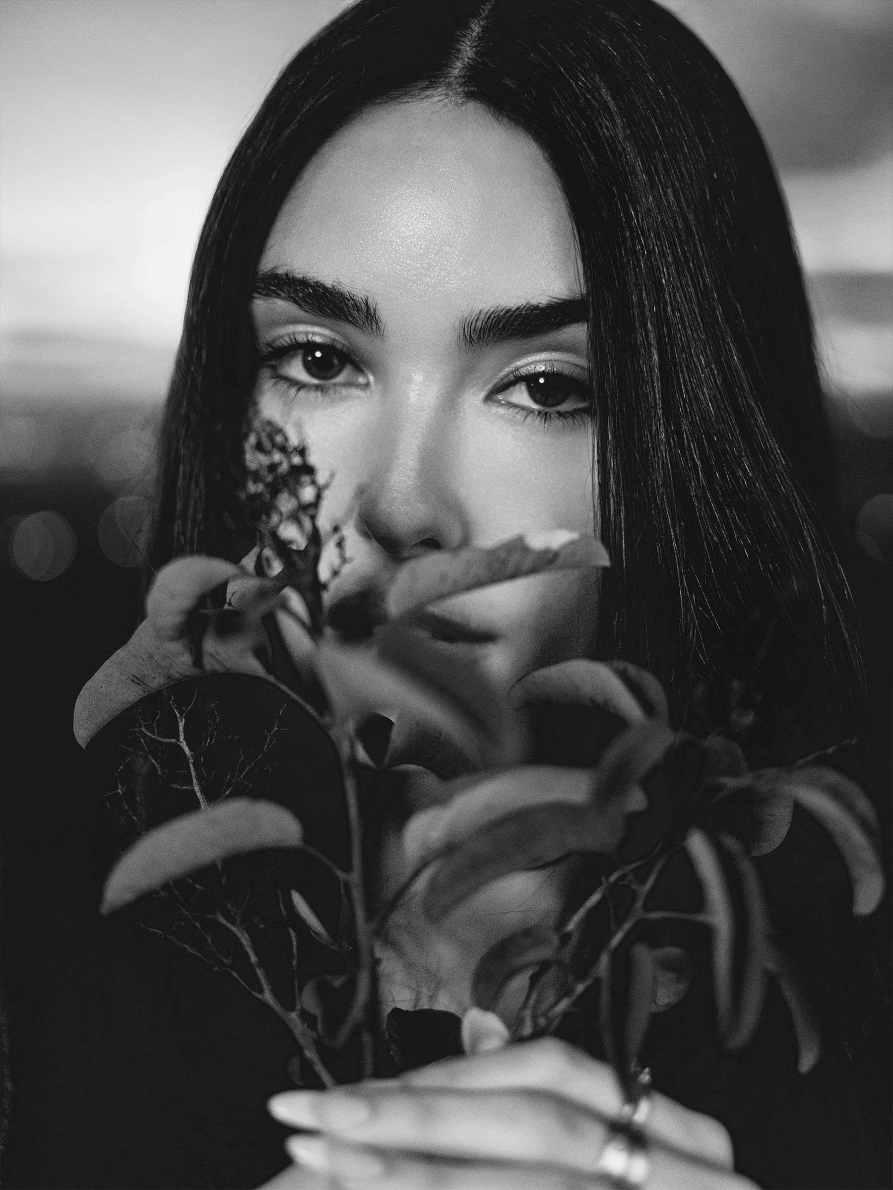 Image from Who What Wear's February cover story with Madison Beer. The photo is black and white and is a close-up of Beer holding a small branch with leaves and a flower in front of her face.