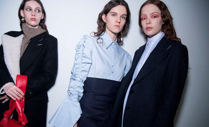 Models wear exaggerated blue shirts, layered with pinstripe blazers.