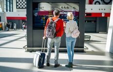 A mature couple with luggage checks the flight schedule at an airport.
