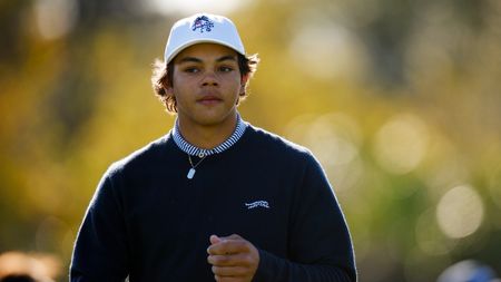 Charlie Woods wearing a white cap and navy sweater 