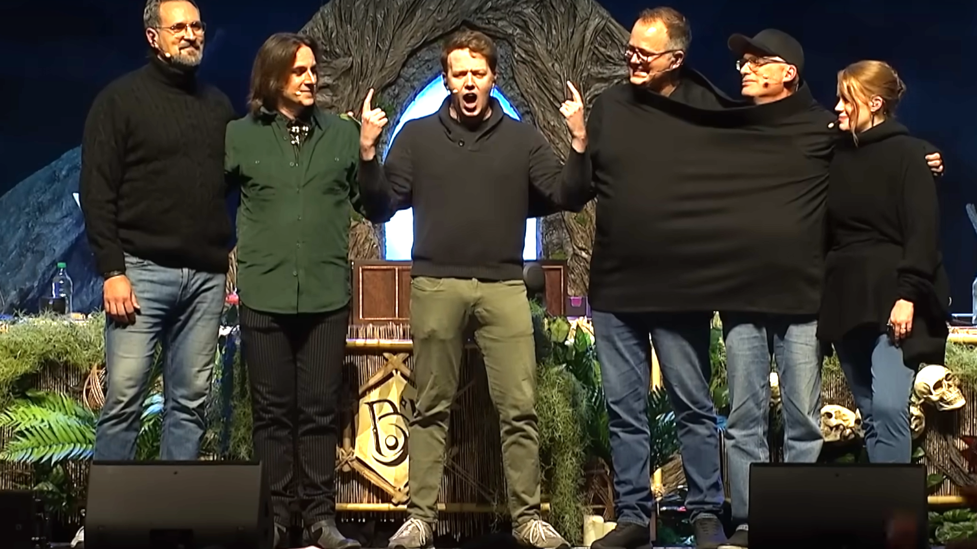 Brennan Lee Mulligan stands on stage with Travis Willingham, Matt Mercer, Chris Perkins and Jeremy Crawford (in a single hoodie), and Marisha Ray - announcing he&#039;ll be the new GM for the next campaign of Critical Role.