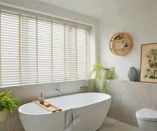 bathroom with paper and wood style window blinds, freestanding bath and bamboo accessories