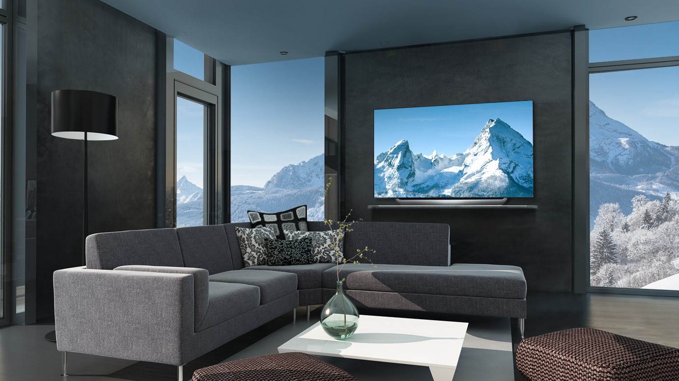 An image of a Samsung TV mounted on a wall in a grey room showing a mountain range on the screen.