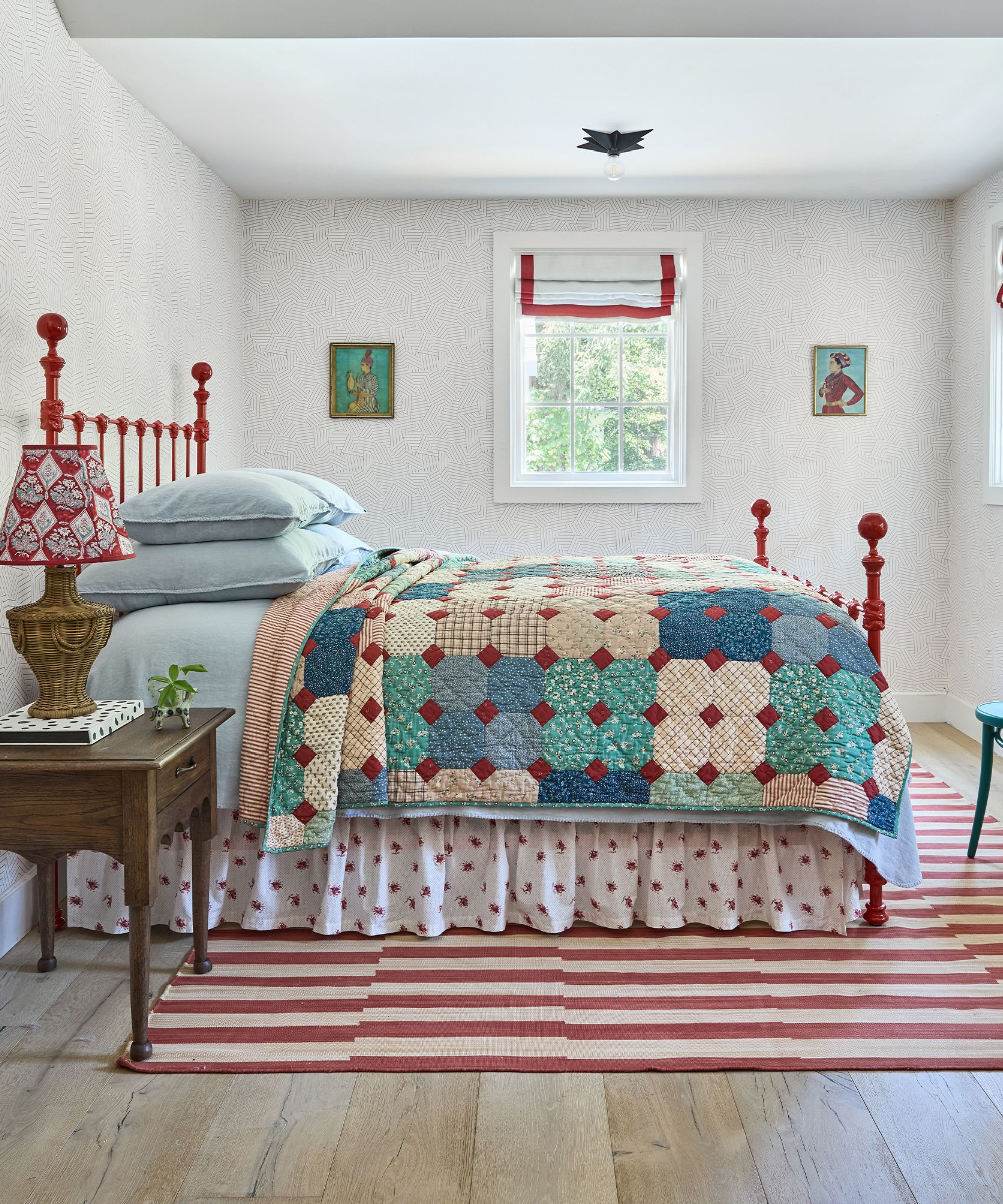 a bedroom with a red and white striped rug, a quilt on the bed, a red bed frame, and blue bed sheets