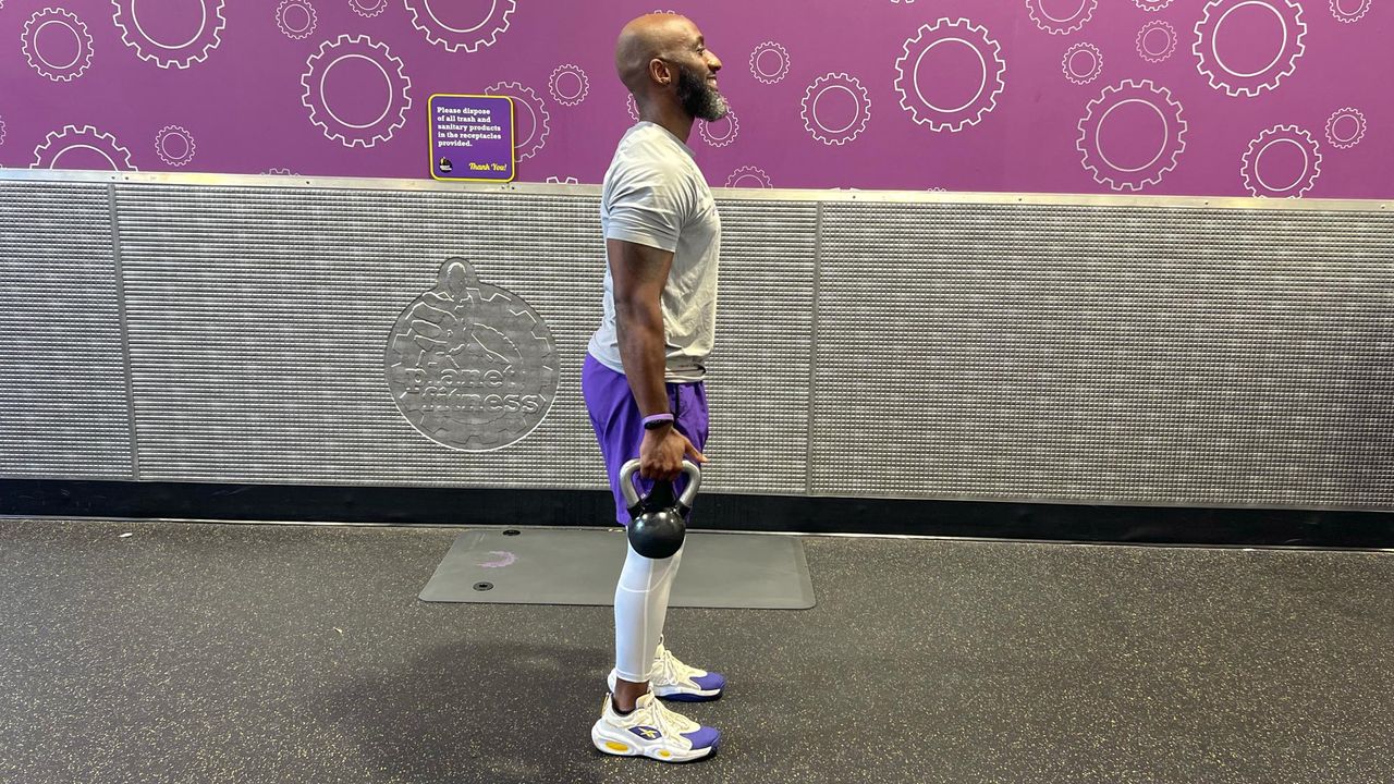Teddy Savage starting an alternating reverse lunge to overhead shoulder press