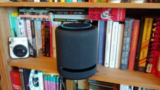 En smart-høyttaler av typen Amazon Echo Studio i en bokhylle.