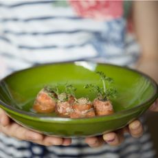 A child holds a green plate of carrot tops