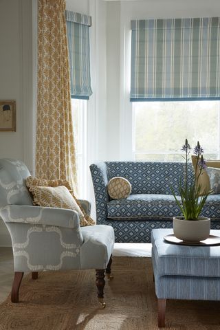 living room with yellow curtains and blue blinds alongside blue sofa and gray armchair