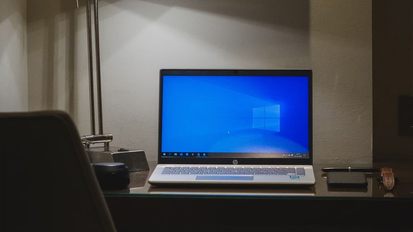 Windows 10 laptop sitting on a desk in a dark room.