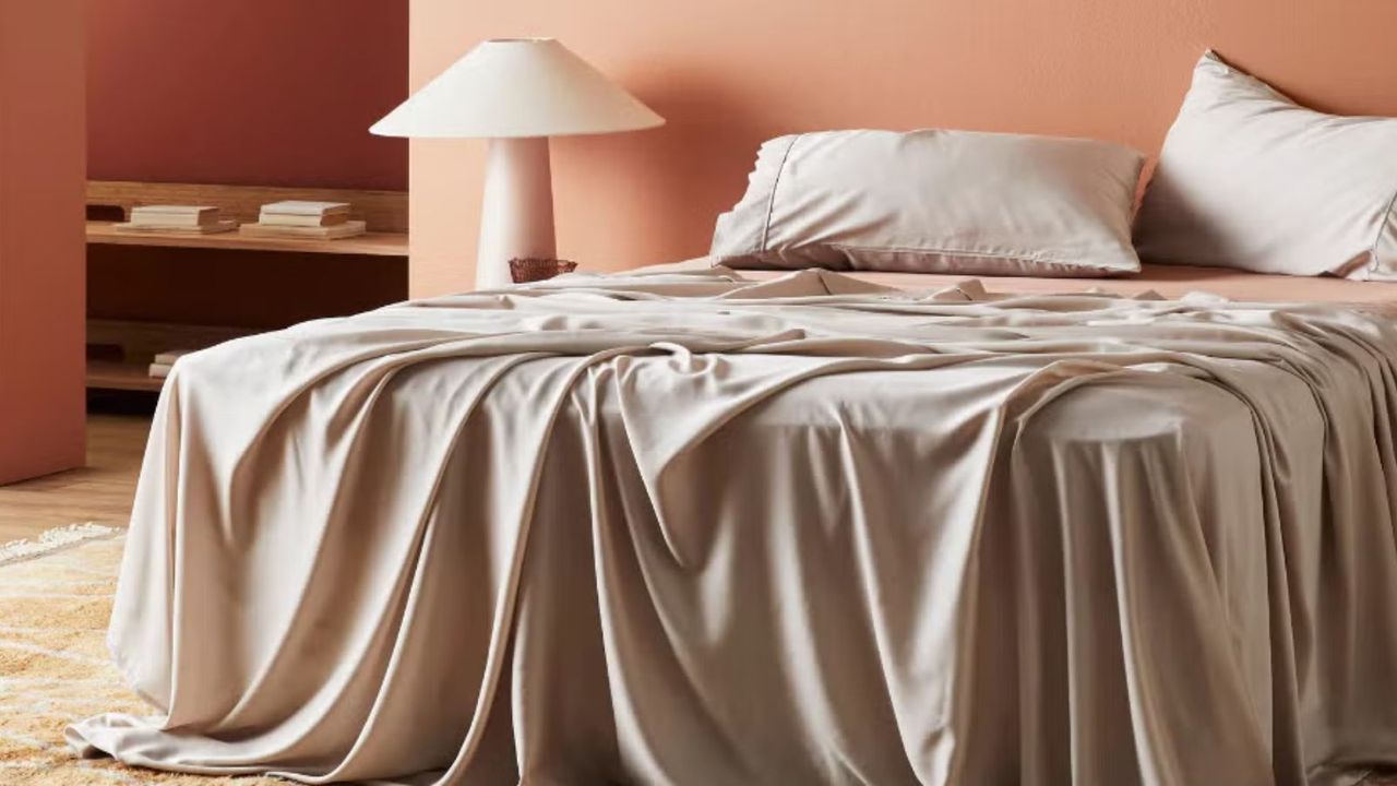 ettitude Signature Sateen Sheets on a bed against peach-colored walls. 